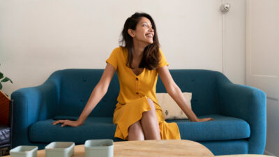 Happy young woman sitting on couch looking sideways